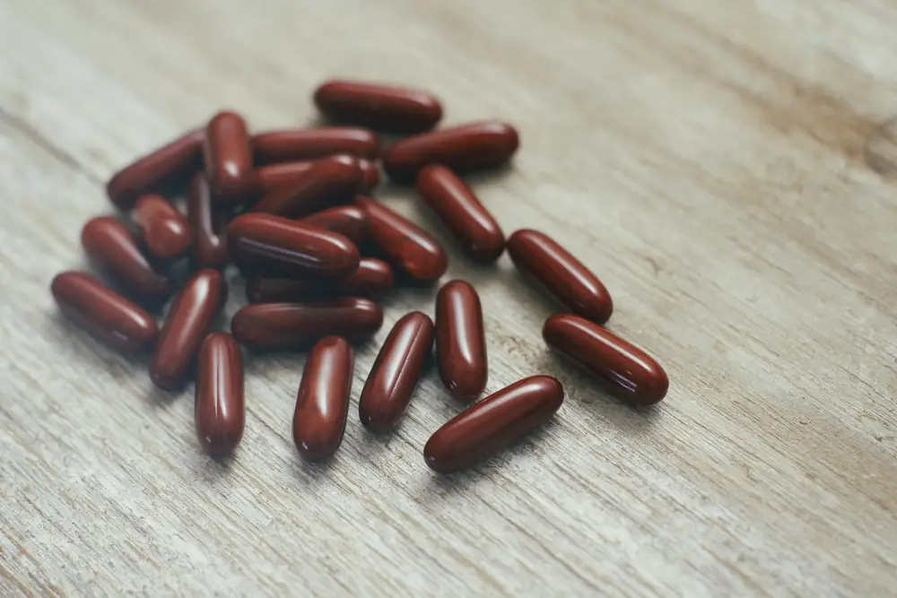 Dark red sleek capsules on wooden background